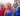 Three smiling Masai women in colorful garbs and festive jewelry